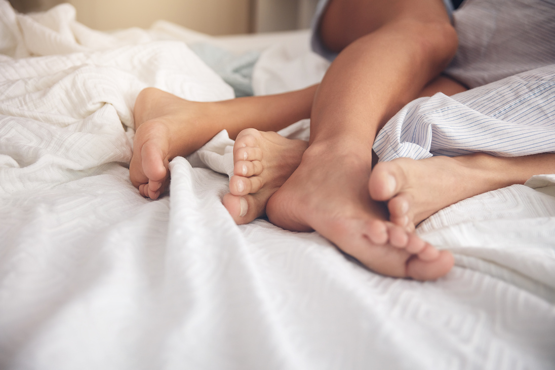 Intertwined feets on a bed